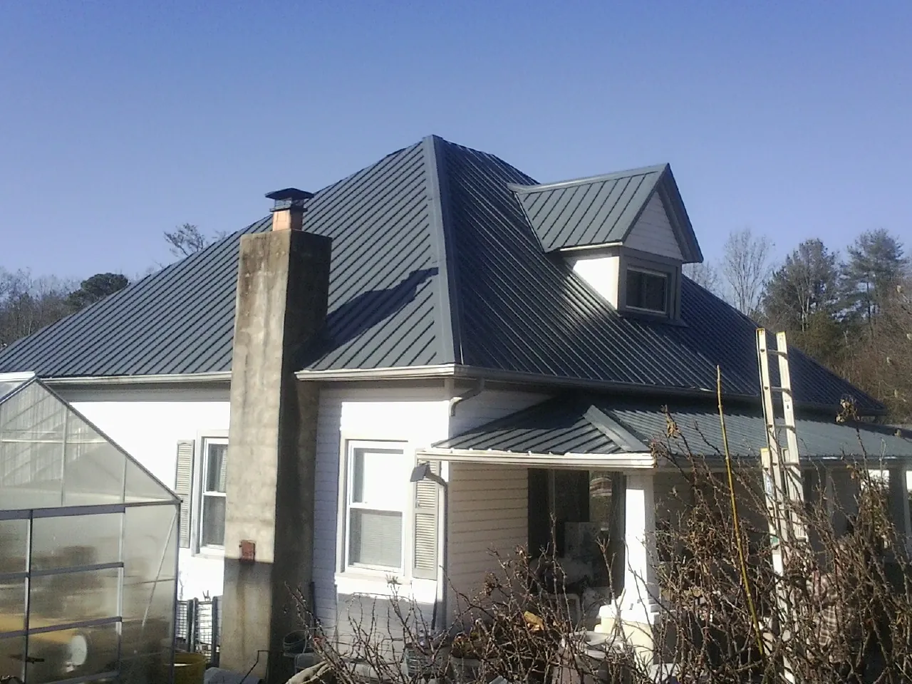 Dark blue standing seam metal roof on a white farmhouse with dormer — Slate & Tile Roof Repair by Roofing Brothers in Sophia