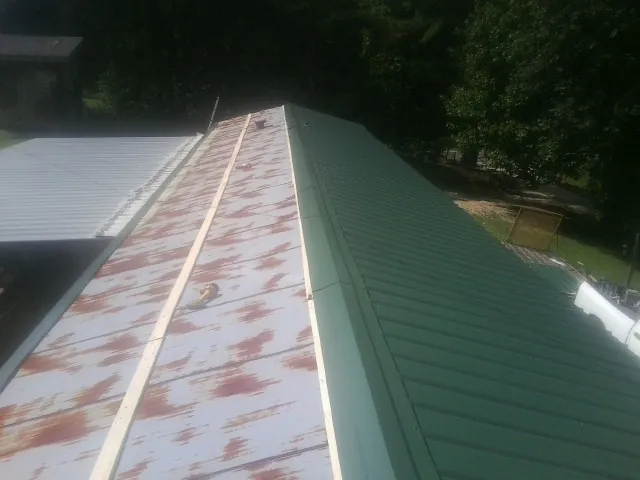 Old rusted panels beside newly installed green metal roofing — Wind Damage Roof Repair by Roofing Brothers in Sophia