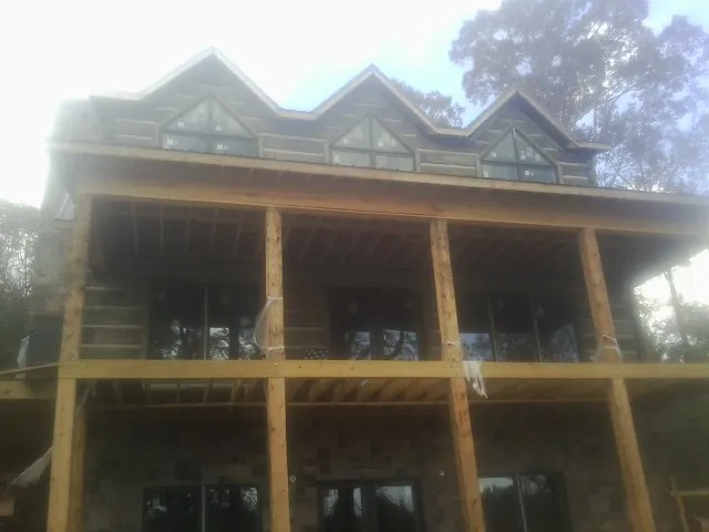Dormers and porch framing on a large log home under construction — Roof Coating work by our crew in Sophia