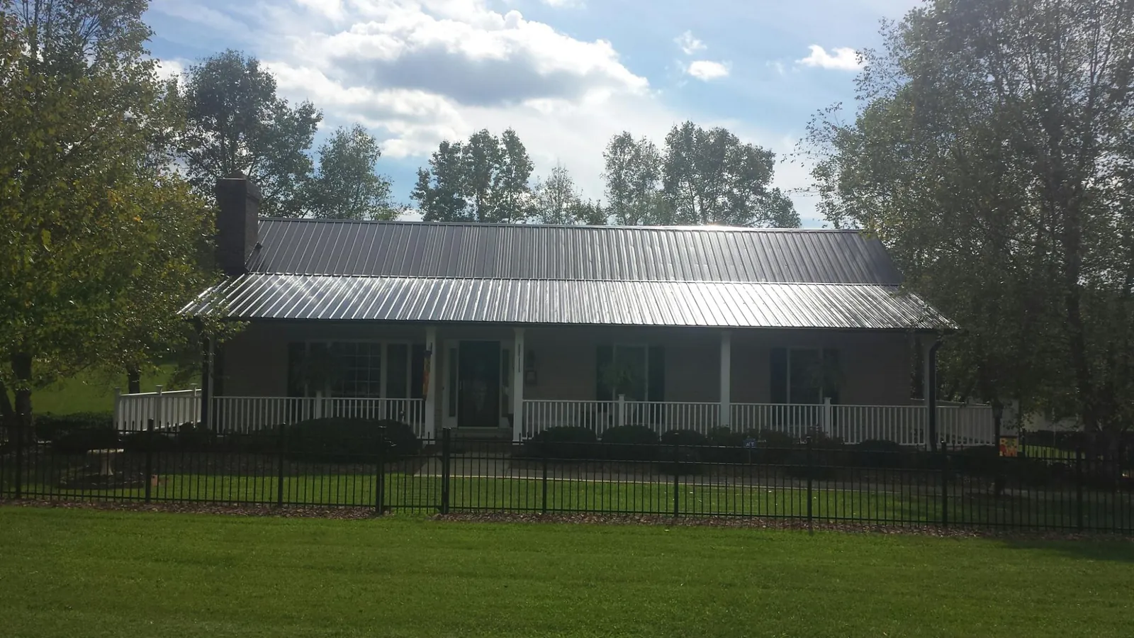 Gray metal roof on a brick ranch with a full width front porch — Gutter Guard Installation work by our crew in Sophia