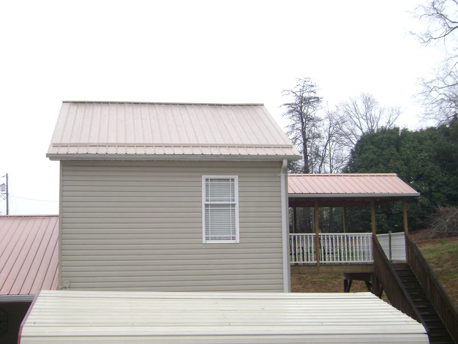 Tan metal roofs on a two story addition and attached porch, from a Roof Replacement job in Sophia