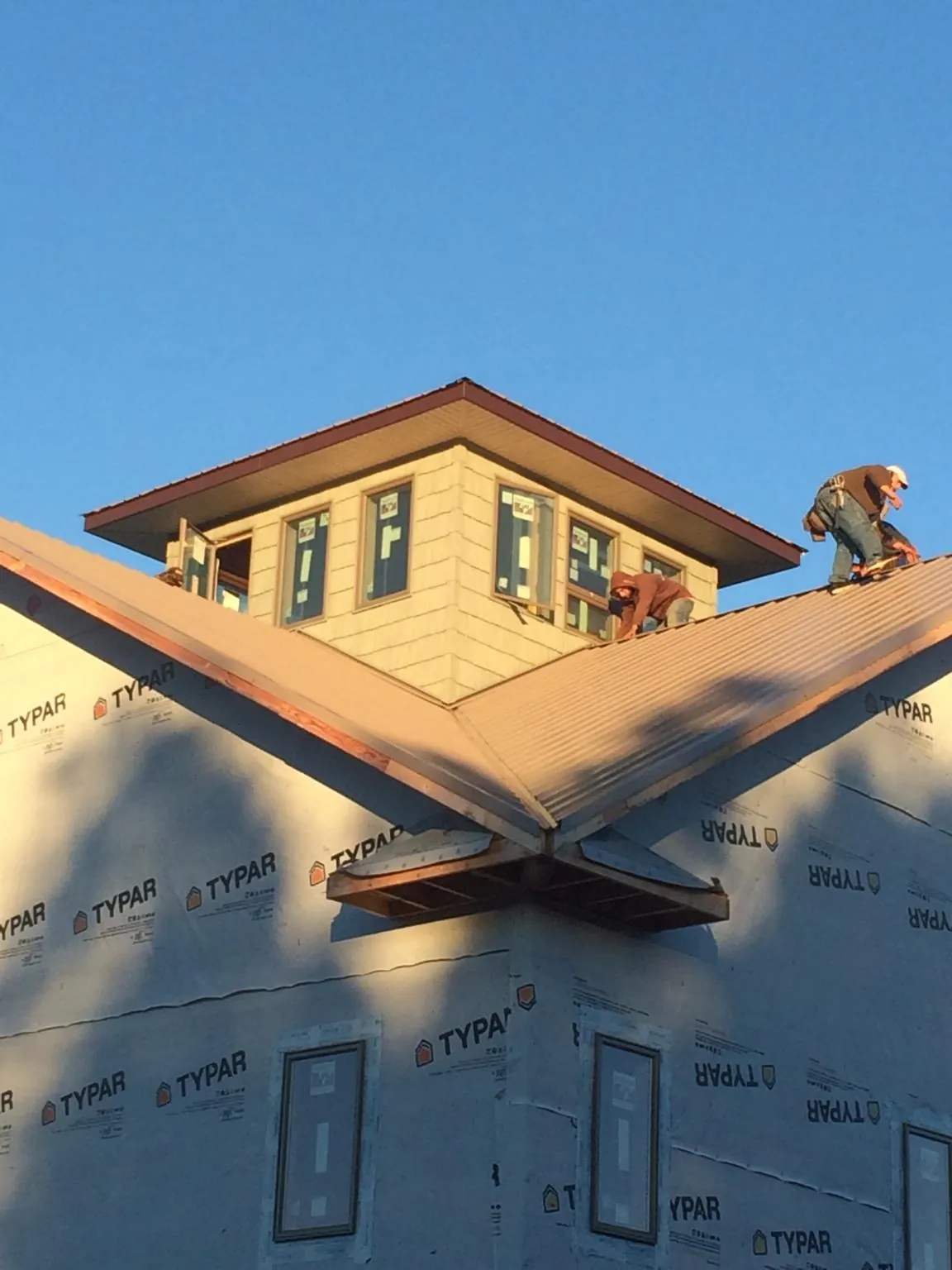 Roofers working around a rooftop cupola on a new metal roof at sunset — Roof Waterproofing in Sophia by Roofing Brothers
